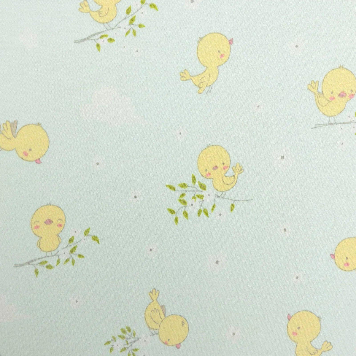 Light blue romper fabric close-up showing repeating yellow chick characters and green sprigs