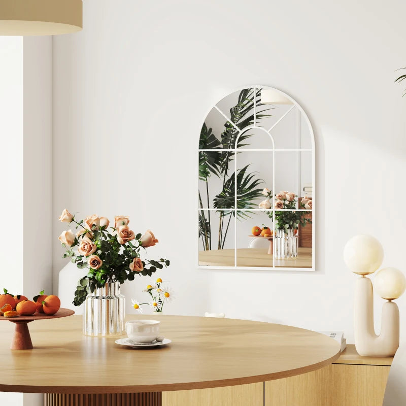 White arched grid mirror with window-style grid reflecting flowers and decor