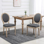 Set of two grey upholstered dining chairs with carved wooden frames