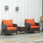 Two brown PE rattan armchairs with orange cushions and matching glass-top side table