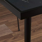 Close-up of black steel table leg and corner with marble-effect tabletop edge
