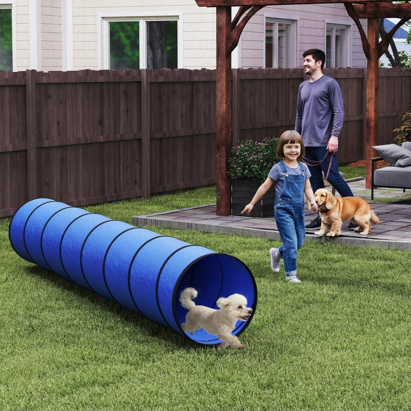 Blue dog agility tunnel with circular open ends, positioned in a backyard yard