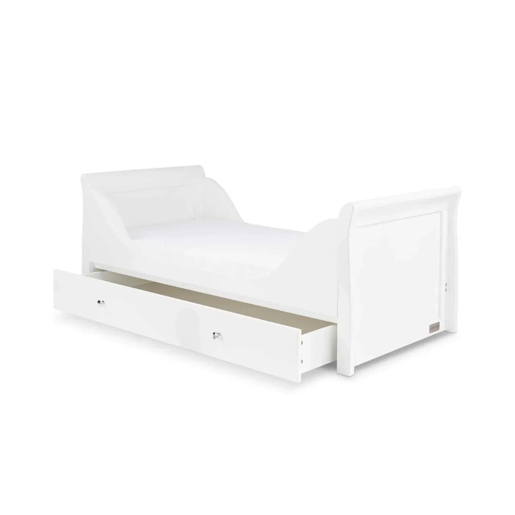 White cot bed with mattress base, side rails, and drawer storage panel