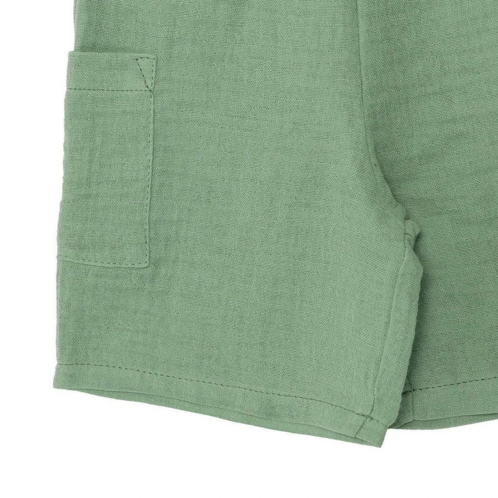 Green muslin baby shorts with patch pocket and stitched hem