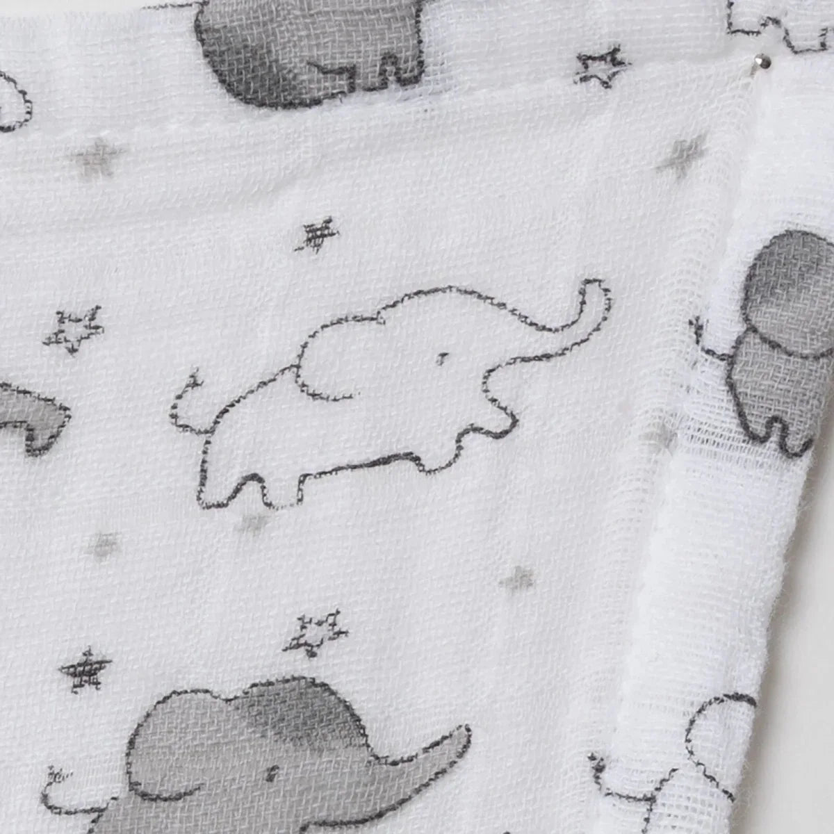 Close-up of white muslin fabric with stitched gray elephant outlines and stars