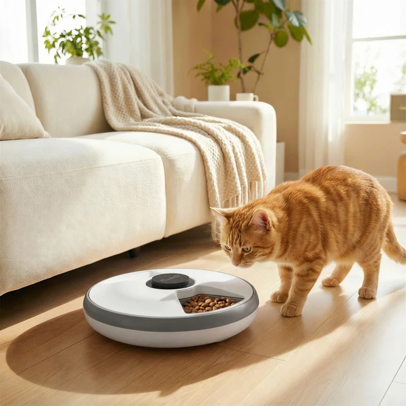 White and grey automatic cat feeder with an orange cat eating from the bowl