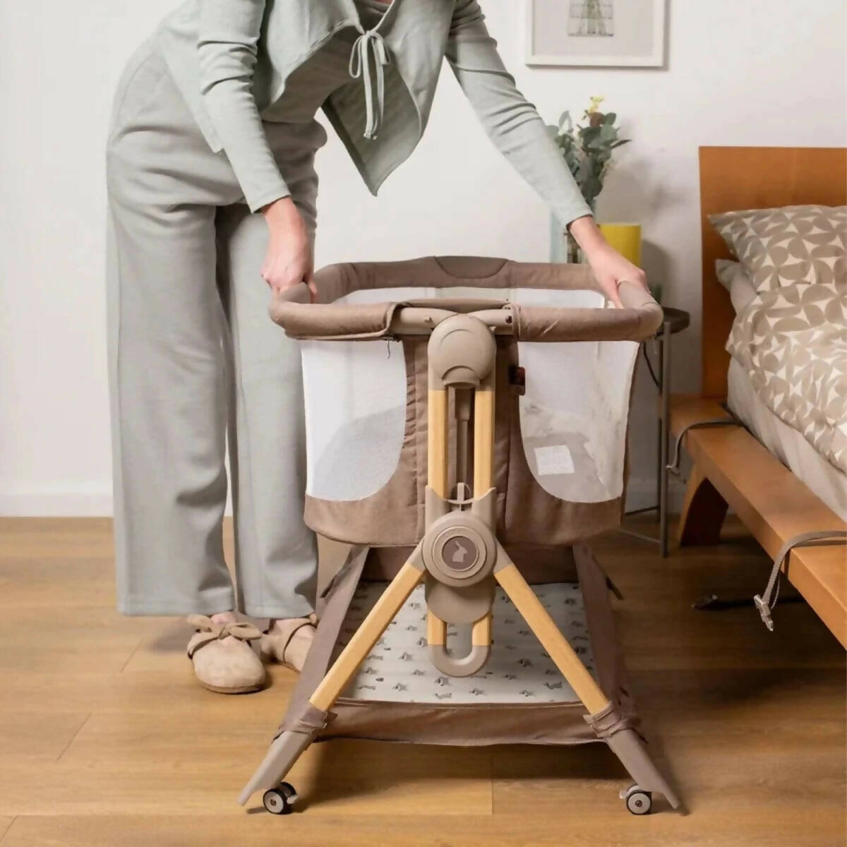 Folding bedside crib open with padded canopy and beige fabric panels