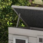 Close view of grey wooden cat house open roof frame and dark asphalt panel