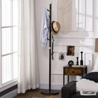 Freestanding coat rack stand with jacket and hat on dark hooks, round base, gold accents