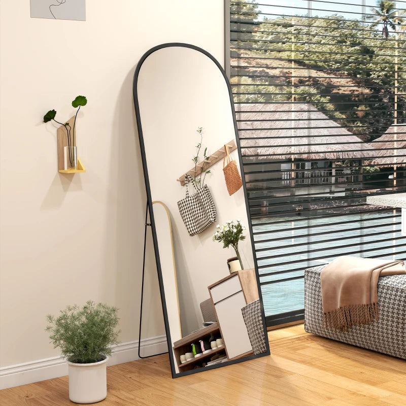 Black arched standing mirror tilted slightly, reflecting the room from the side