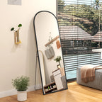 Black arched standing mirror tilted slightly, reflecting the room from the side