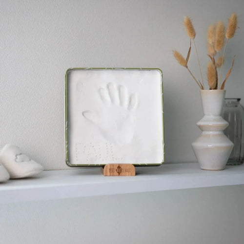 Olive green framed baby hand imprint square with white cast on display stand