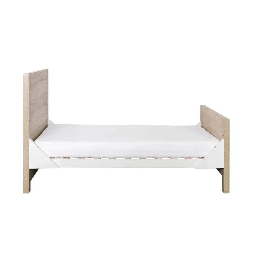 Oak and white wooden cot bed with side rails and padded mattress