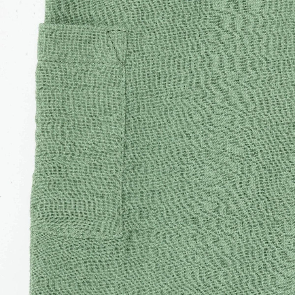 Green muslin baby shorts patch pocket close-up with stitched corners