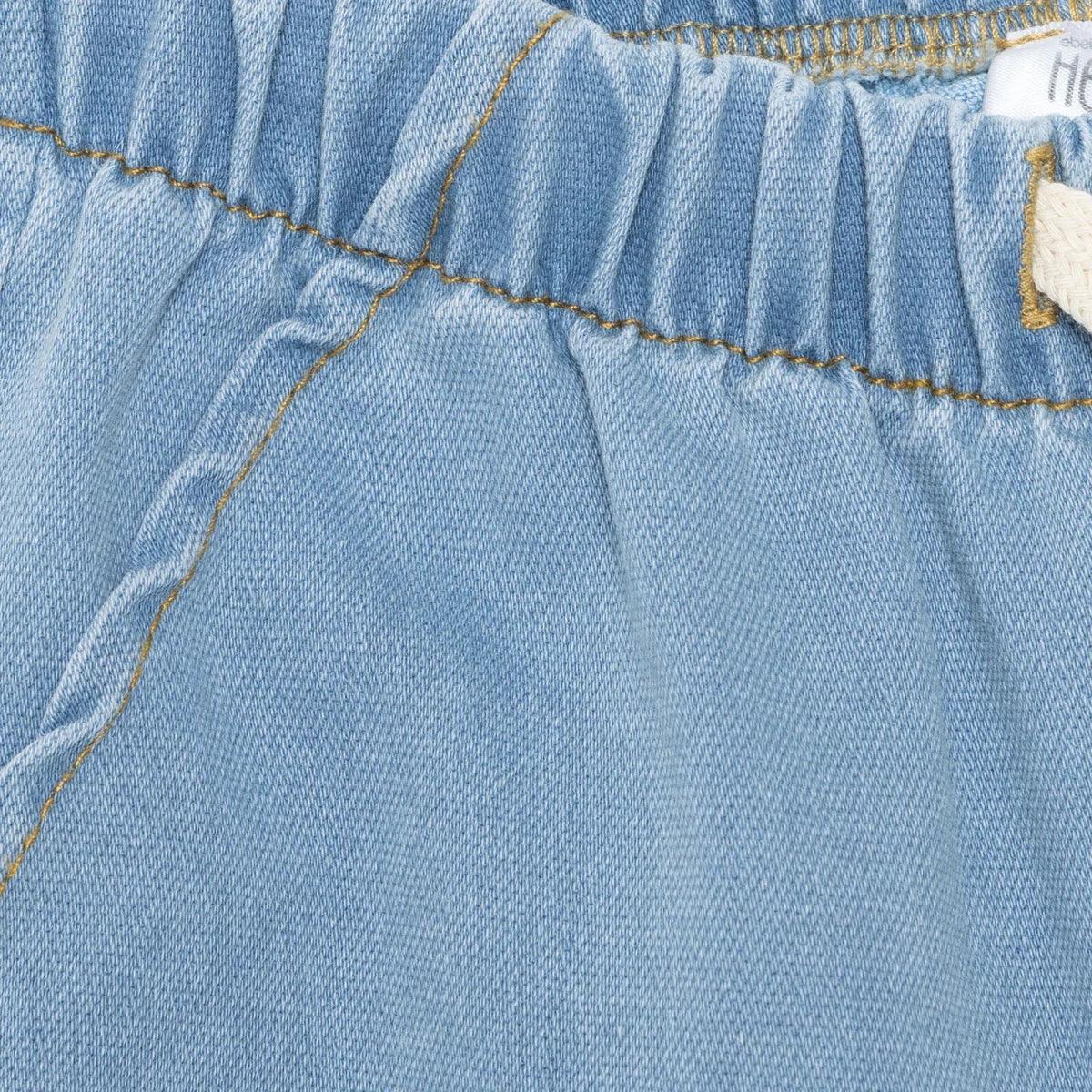 Light blue denim baby trousers close-up of seam lines and waistband stitching