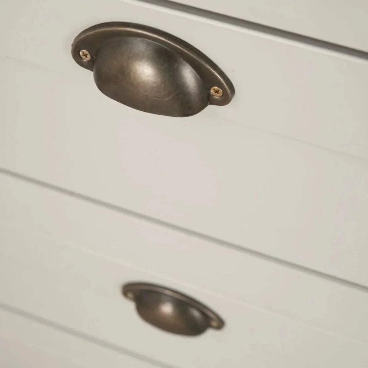 White dresser drawer fronts with curved bronze metal knobs
