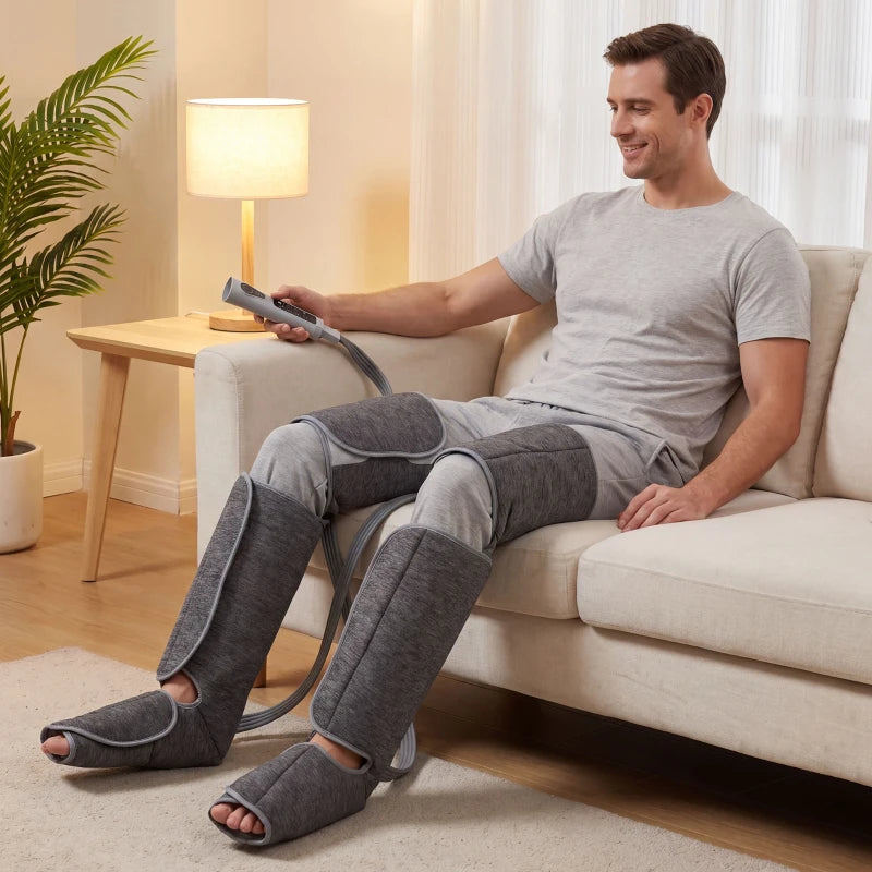 Grey heated leg compression massager on calves and feet, controller held in hand