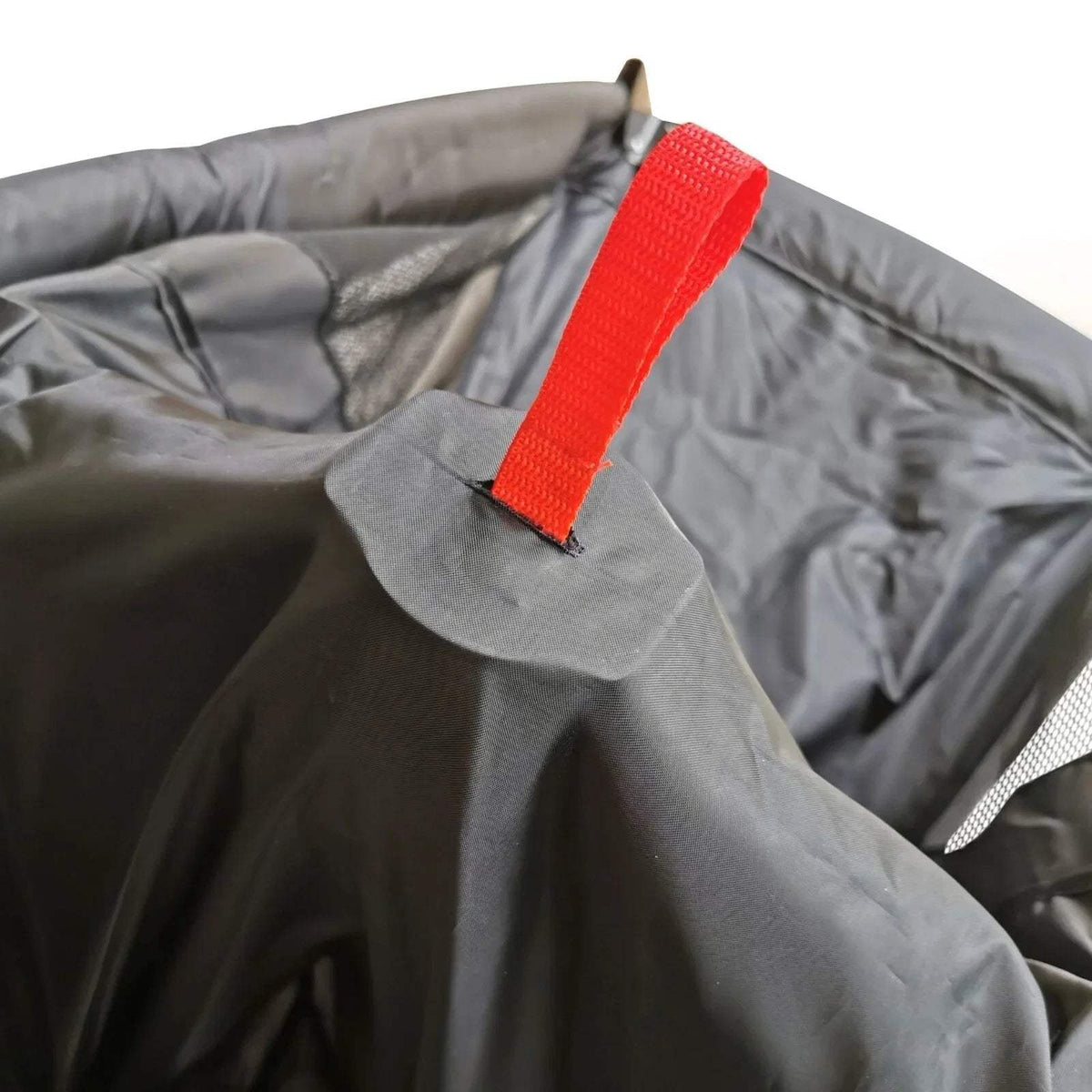 Black travel cot strap detail with bright red webbing on padded rim