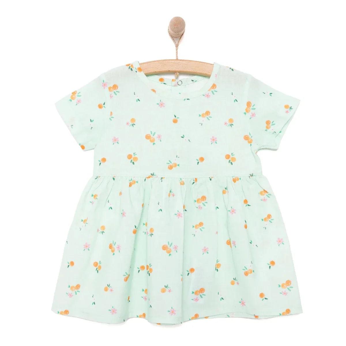 Light blue floral newborn dress with short sleeves and gathered skirt on wooden hanger