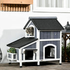 Grey wooden cat house with flower pot, arched entrance, pitched roof and side door