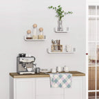 White floating wall shelves on kitchen wall, holding cups, plants, and jars.