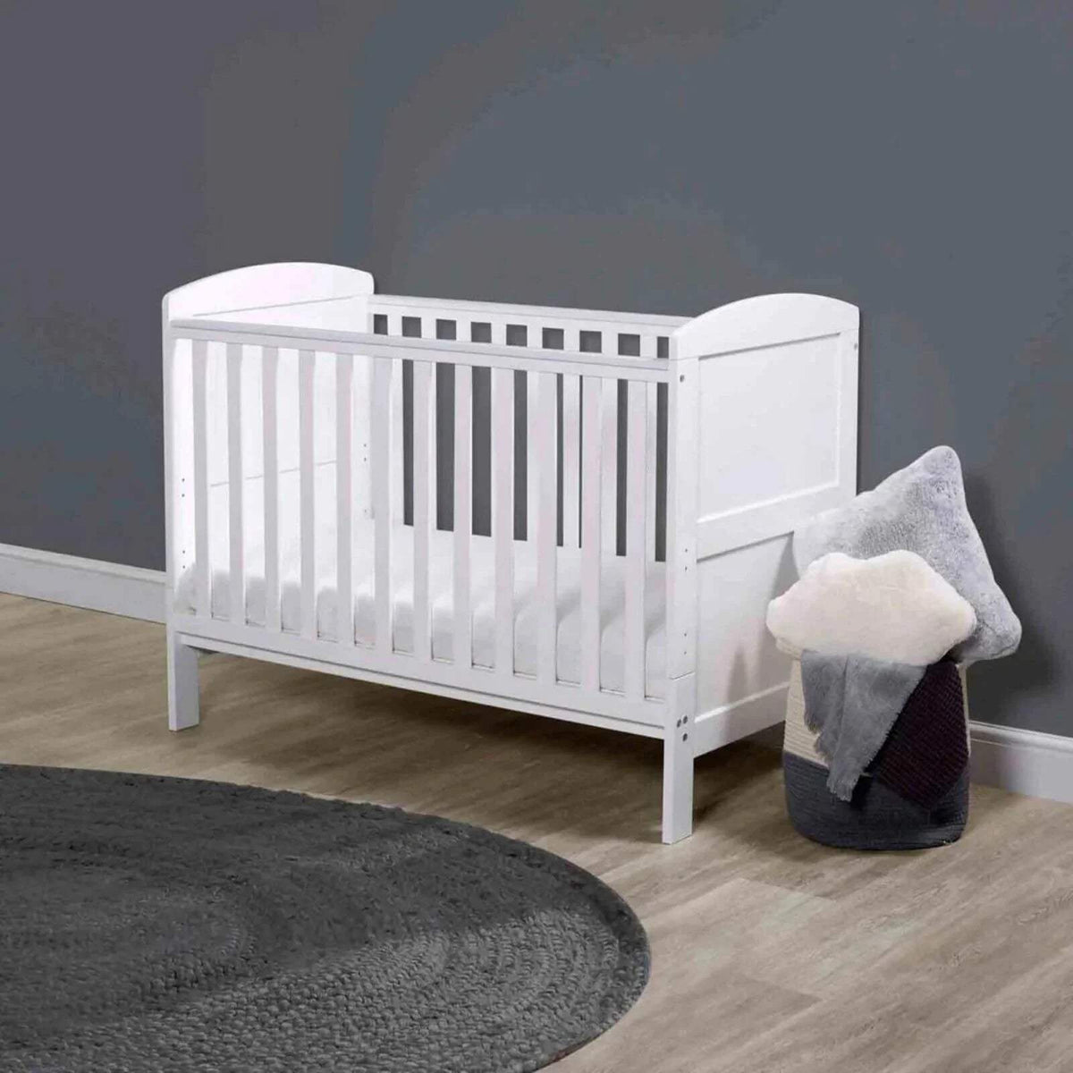 White mini cot bed with vertical slats, end panels, and rounded posts, without mattress