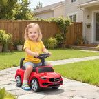 Red Mercedes-Benz ride-on car with child seated outdoors, black steering wheel