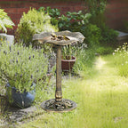 Bronze-tone standing bird bath with lotus leaf basin and bird perched on edge