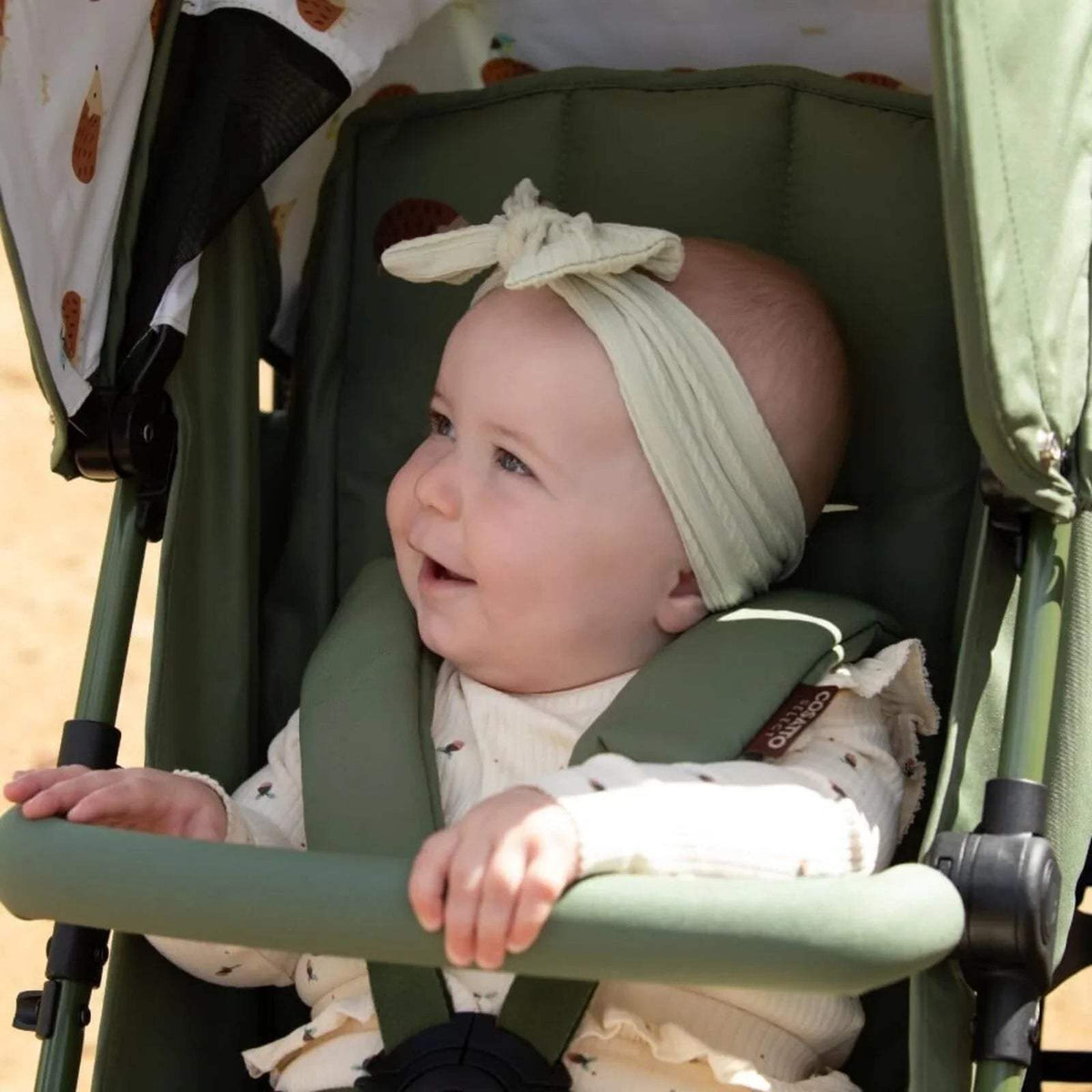 Cosatto Supa 3 stroller interior view with baby in light top and green padded seat