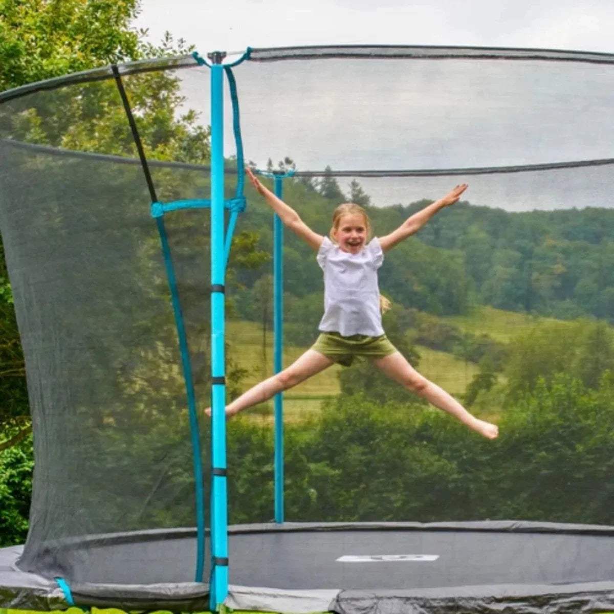 Child jumping inside trampoline, arms out, gray mat and blue frame