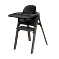 Black highchair with rounded backrest, black tray, and warm brown wooden legs