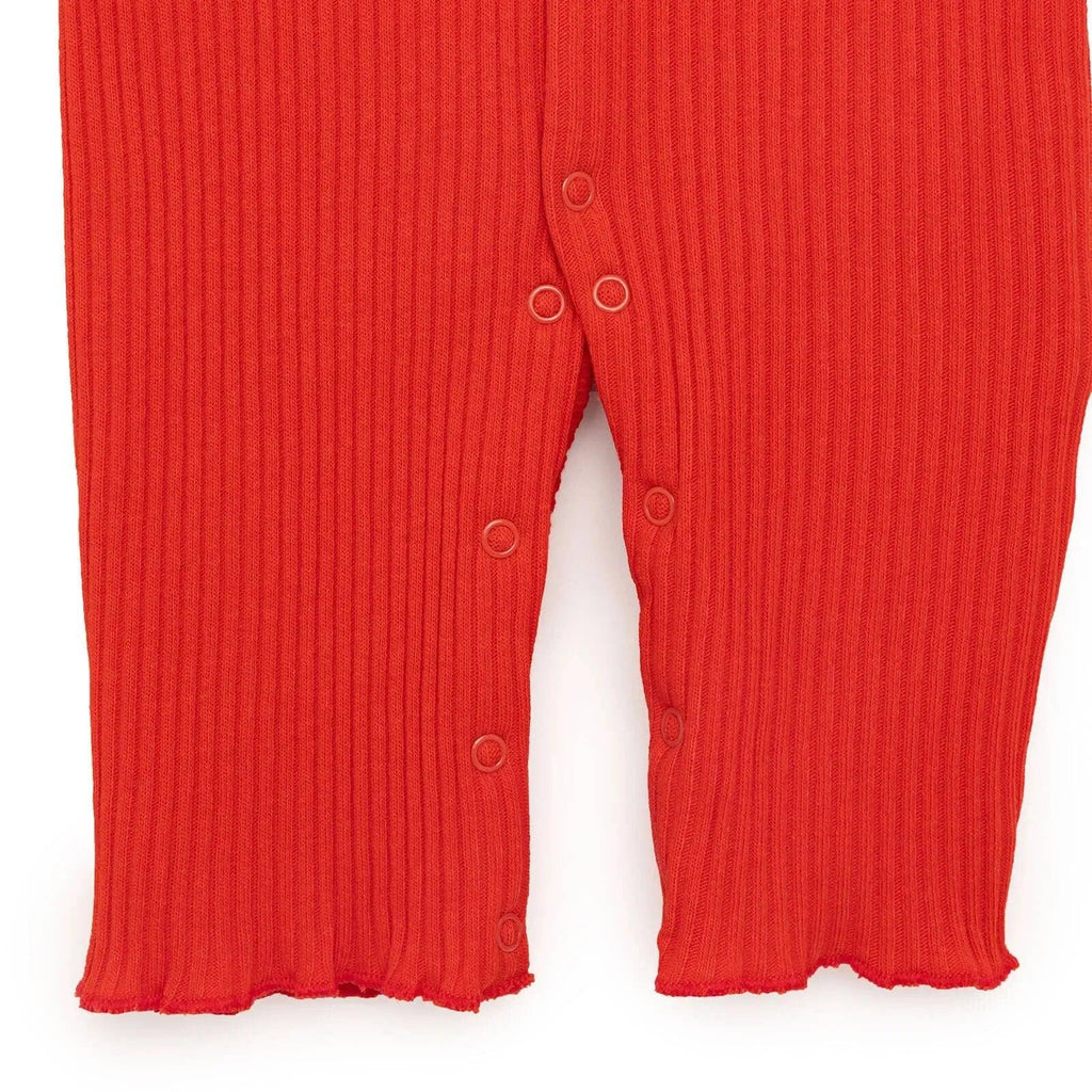 Orange rib-knit jumpsuit with snap buttons along the inseam