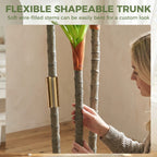 Flexible artificial dracaena trunks with green leaves in a white pot.