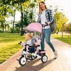 Pink kids trike with canopy and parent push handle, outdoor walkway