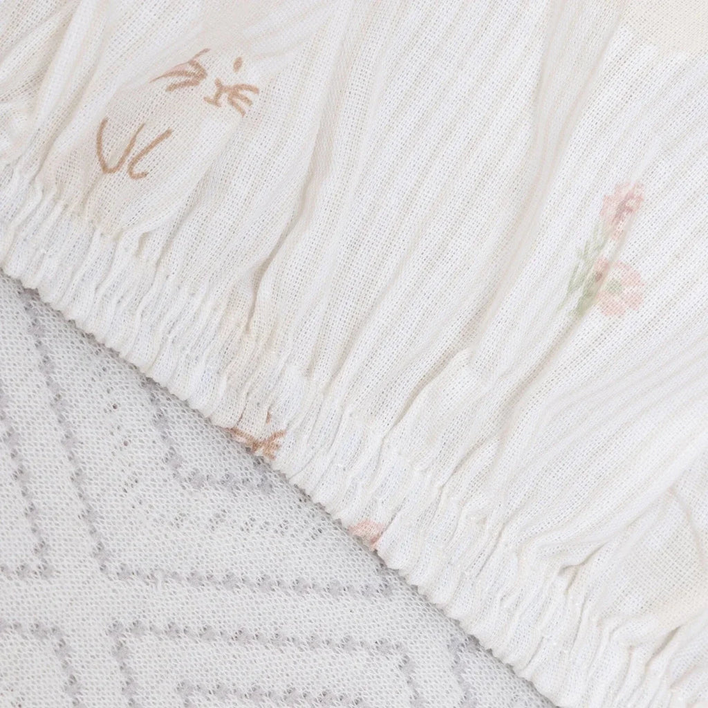 White baby sheet edge with textured stitching and small pastel floral motifs