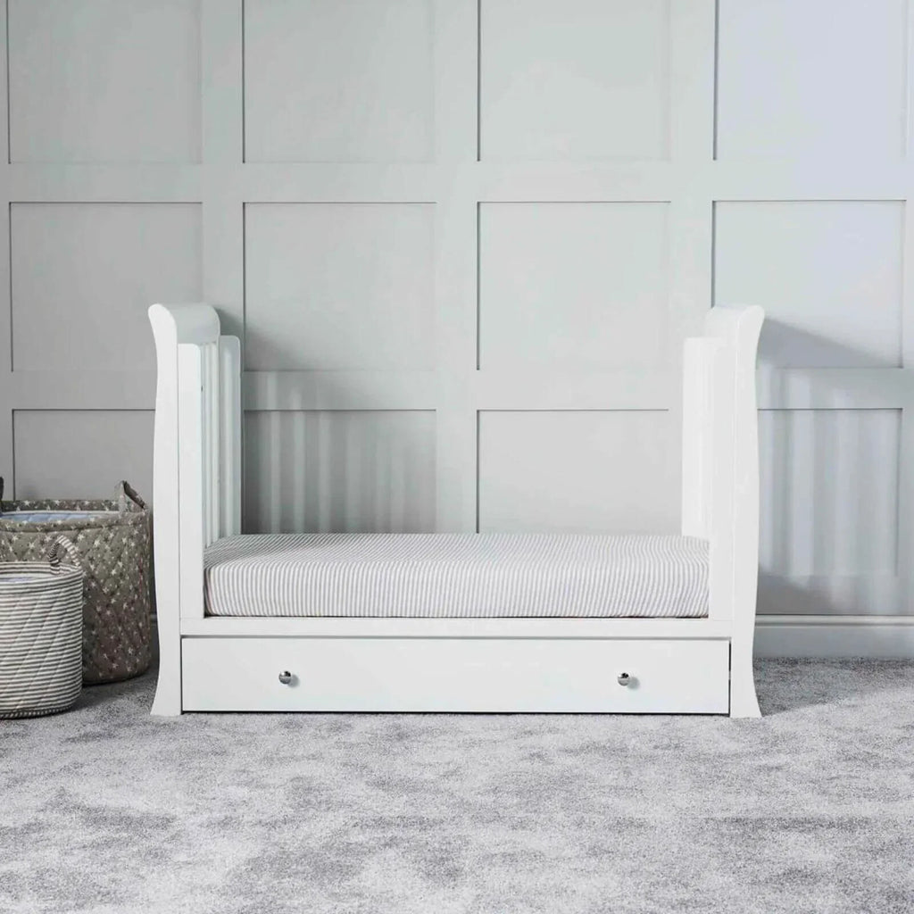 White mini cot bed with front drawer and striped mattress, without accessories