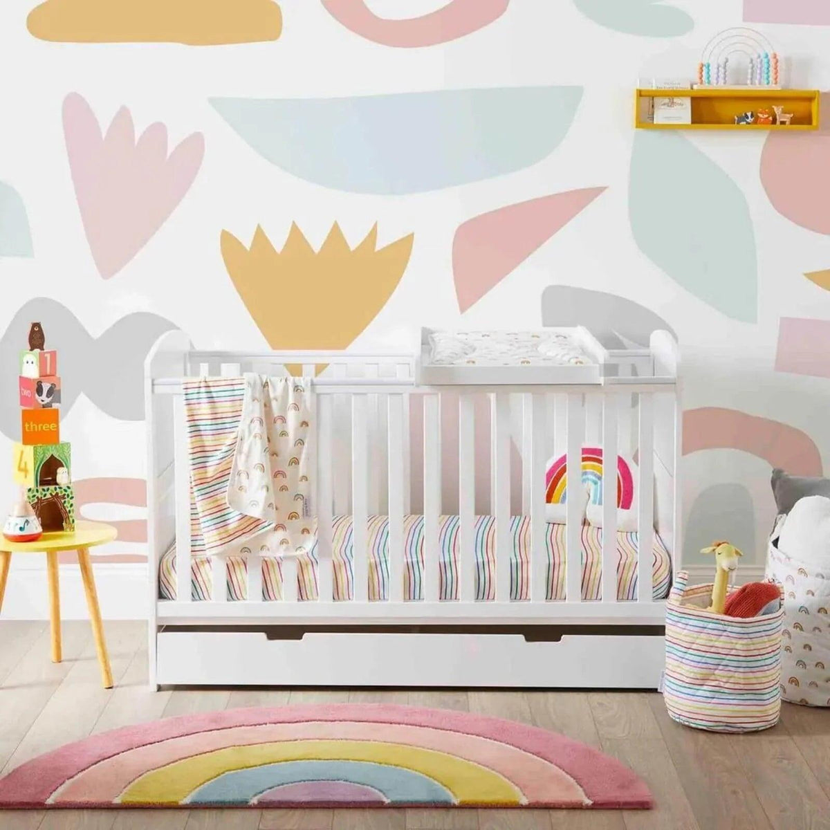 White cot bed with under drawer in a nursery, visible rails and drawer front