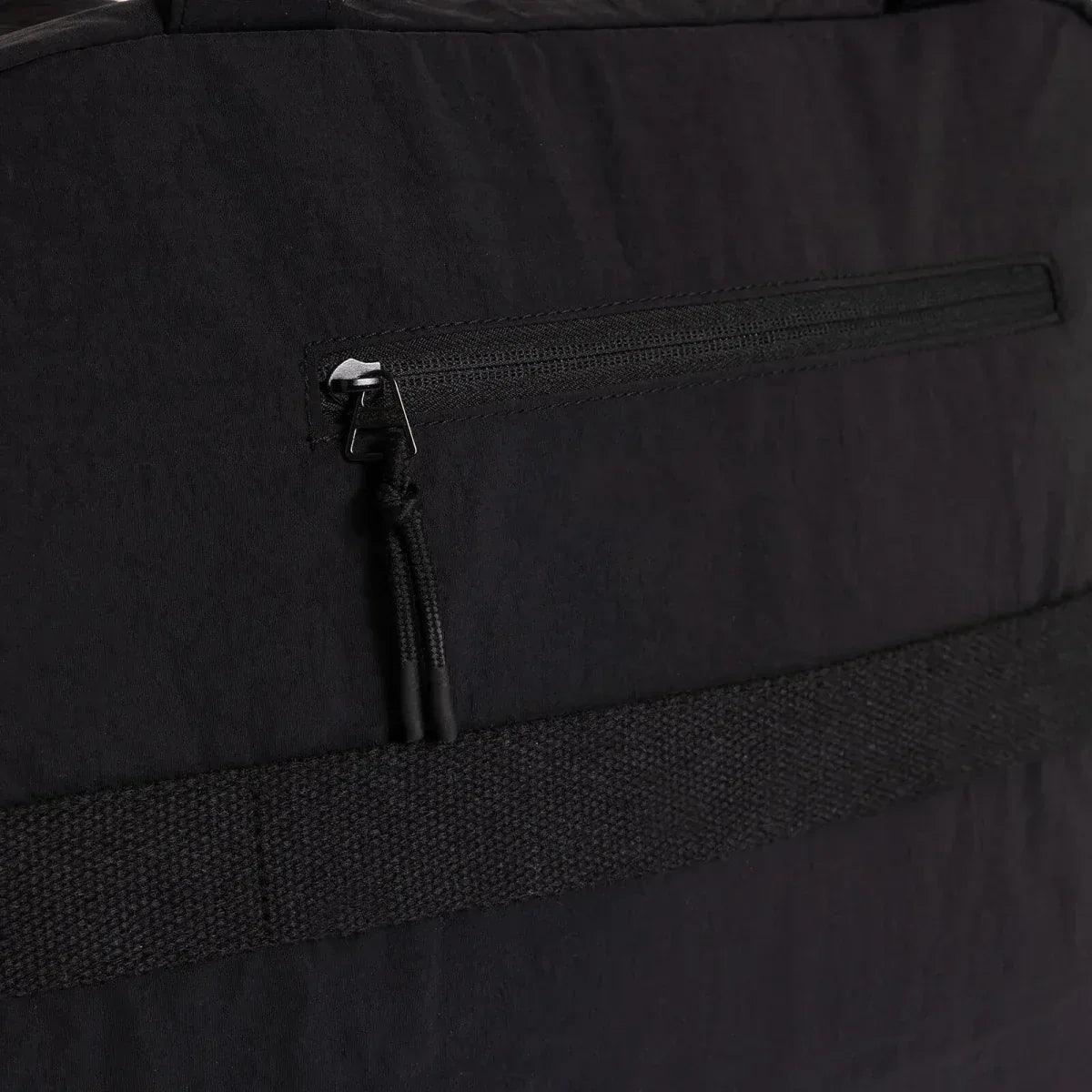 Black quilted shoulder bag close-up of front zipper pocket and metal pull tab