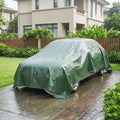 Green waterproof tarpaulin car cover with secured lower edge and grommet corners