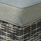 Grey seat cushion corner with stitched edging and woven grey rattan base
