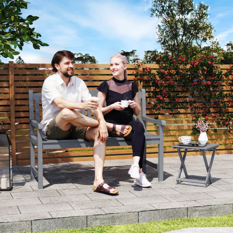 Grey 2-seater garden bench outdoors with decorative backrest and armrests