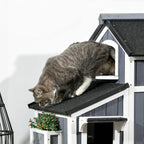 Grey tabby cat resting on the top platform of a grey wooden cat house