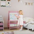 Pink kids art easel with whiteboard panel and front storage bins while a child draws