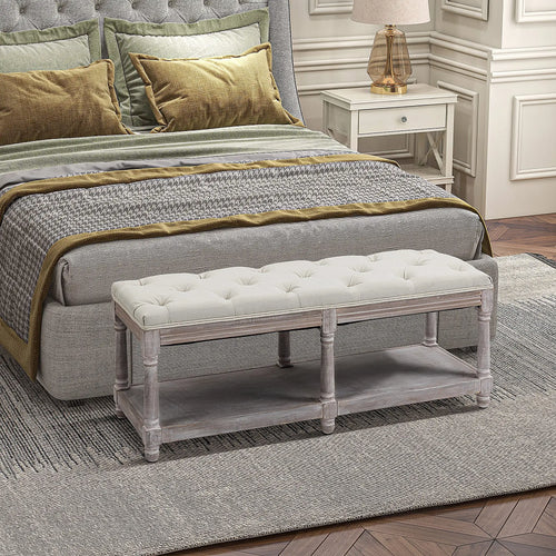 Cream tufted wooden bench placed at the foot of a bed, with a lower shelf