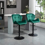 Pair of green velvet bar stools with tufted backs, black pedestal bases and footrest rings