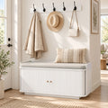 White hallway storage bench with top seat and wall coat hooks over closed cabinet