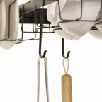 Black utensil hooks and hanging holders under a drying rack beneath plates