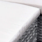 Beige seat cushion corner with piped seam on woven grey rattan ottoman