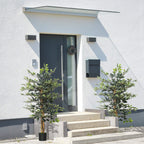 Artificial ficus tree pair in black pots beside an entryway