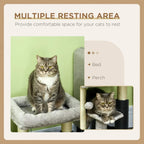 Grey cat tree with cushioned bed and scratching posts, with a cat on the perch.